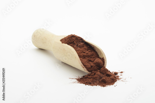 Cacao en polvo y cuchara de madera sobre fondo blanco