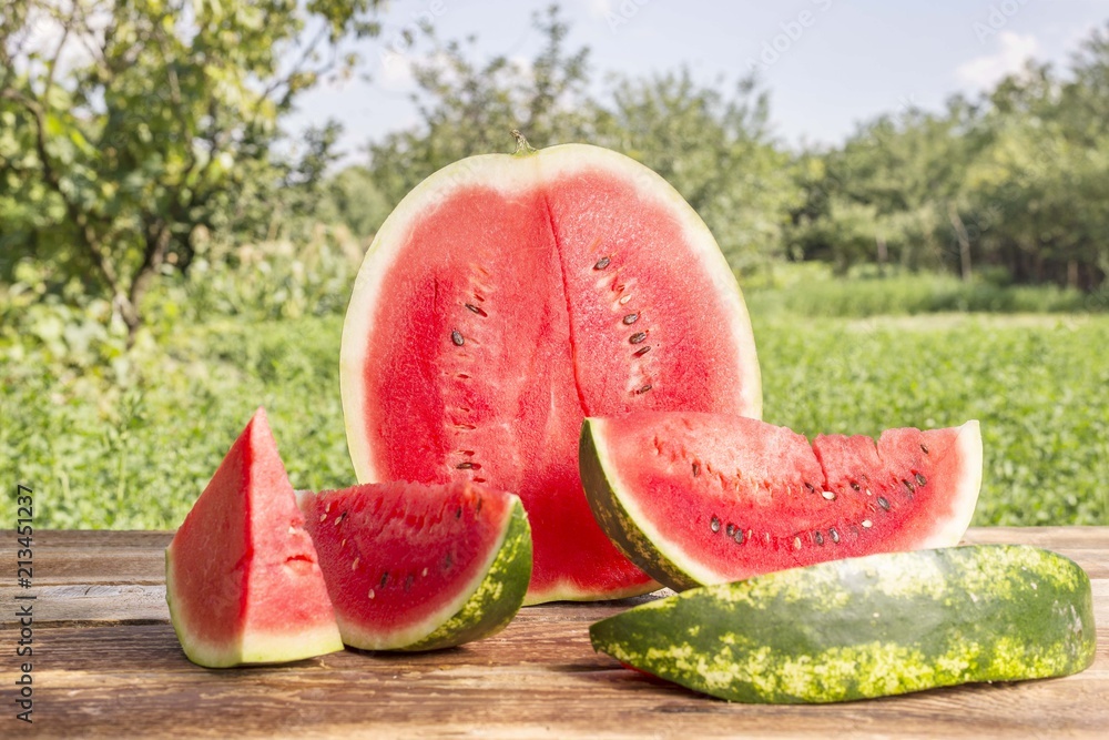 Half of watermelon with slices isolated on wooden table Half of watermelon with slices isolated on wooden table