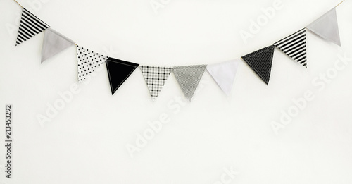 Cute triangle bunting flag gray, white, black color polka dot, plaid, striped pattern design hanging for party decorated on wall room with copy space for text.birthday or festival concept