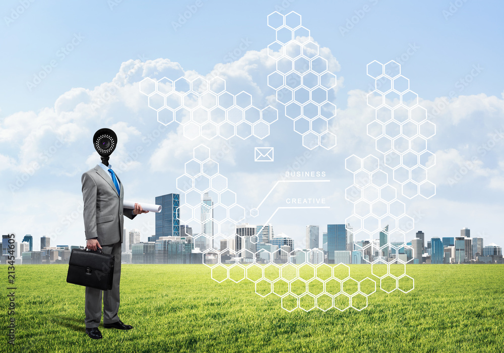 Camera headed man standing on green grass against modern cityscape Camera headed man standing on green grass against modern cityscape