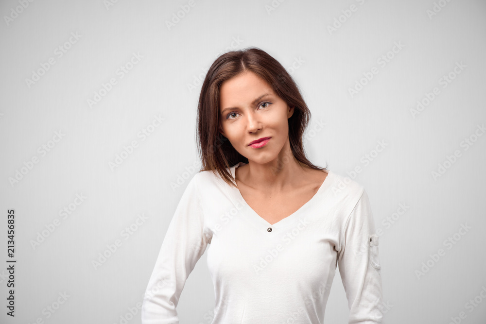 Pretty smiling joyfully female with dark hair, dressed casually, looking with satisfaction at camera, being happy. Studio shot of good-looking beautiful woman isolated against blank studio wall Pretty smiling joyfully female with dark hair, dressed casually, looking with satisfaction at camera, being happy. Studio shot of good-looking beautiful woman isolated against blank studio wall