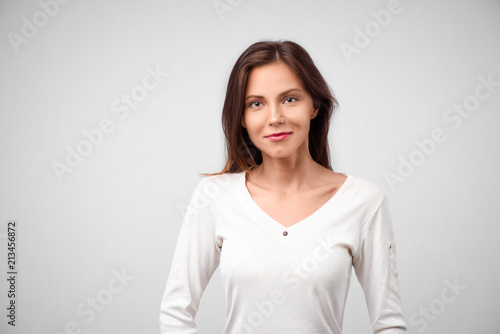 Close up portrait of young cheerful beautiful girl with dark long hair in casual gray shirt smiling  looking in camera with happy and relaxed face expression  posing for university photo