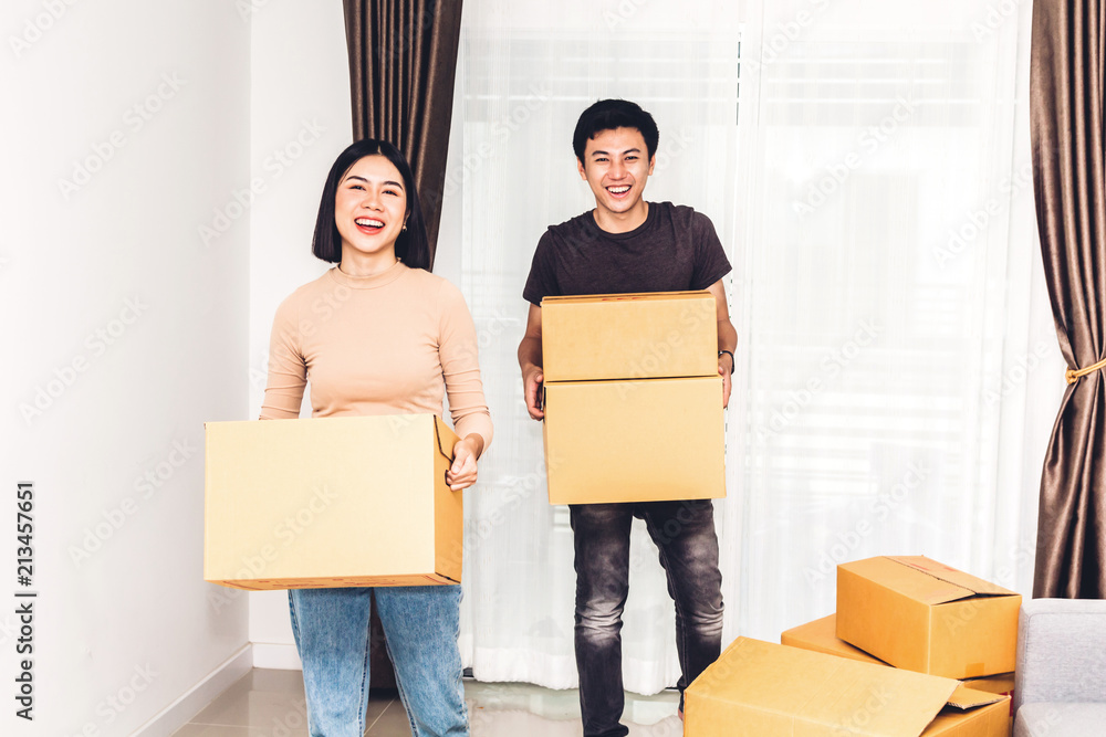 Happy young couple holding box and moving into their new home.House moving and real estate concept Happy young couple holding box and moving into their new home.House moving and real estate concept
