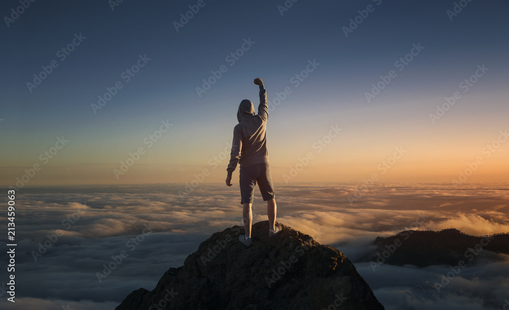 On the top of the world. Man on top of the mountain above the clouds.