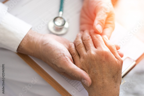 Geriatric doctor or geriatrician concept. Doctor physician hand on happy elderly senior patient to comfort in hospital examination room or hospice nursing home or wellbeing county.