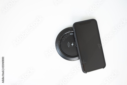 Black mobile phone and Wireless charger on the white screen photo