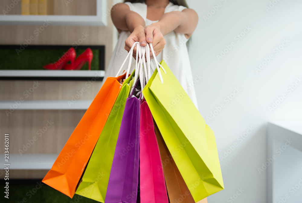 Woman hand is holding the colourful paper shopping bag - Close up