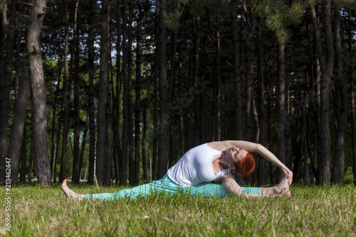 Excercise in nature Redhead girl stretcing out in the park photo