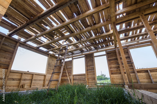 New wooden house under construction. Close-up of walls and ceiling frame with windows openings from inside. Ecological dream home of natural materials. Building, construction and renovation concept.