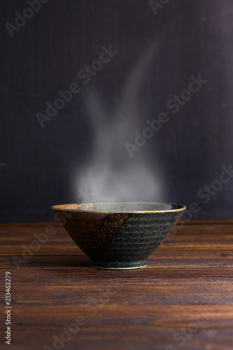 Ceramic bowl with smoke on wooden table.