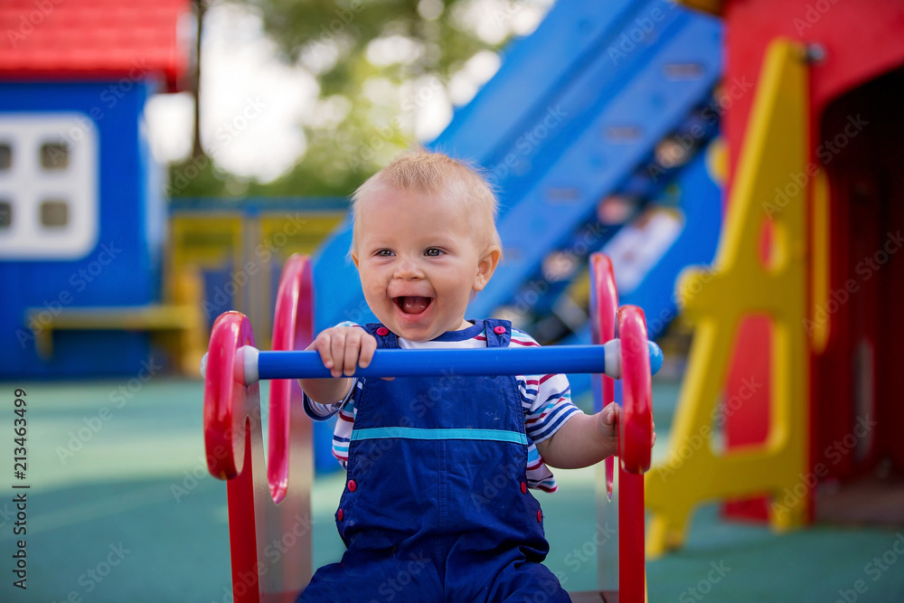 Adorable little 1-2 year old toddler boy having fun on playground, child playing Adorable little 1-2 year old toddler boy having fun on playground, child playing