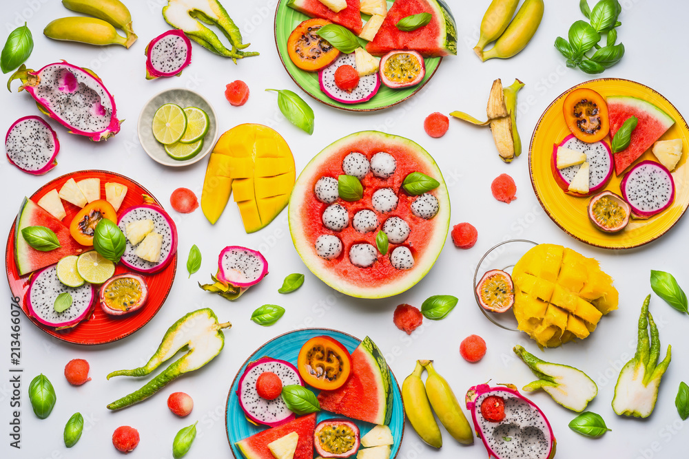 Flat lay of summer various colorful sliced tropical fruits and berries in plates and bowls on white background, top view. Clean and healthy lifestyle background Flat lay of summer various colorful sliced tropical fruits and berries in plates and bowls on white background, top view. Clean and healthy lifestyle background