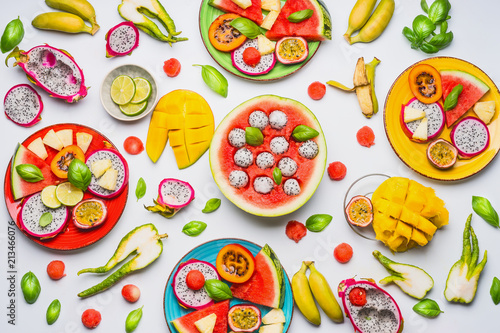 Fototapeta Naklejka Na Ścianę i Meble -  Flat lay of summer various colorful sliced tropical fruits and berries in plates and bowls  on white  background, top view.  Clean and healthy lifestyle  background