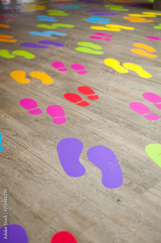 Shot of many colorful footsteps on a wooden floor that are crowding together