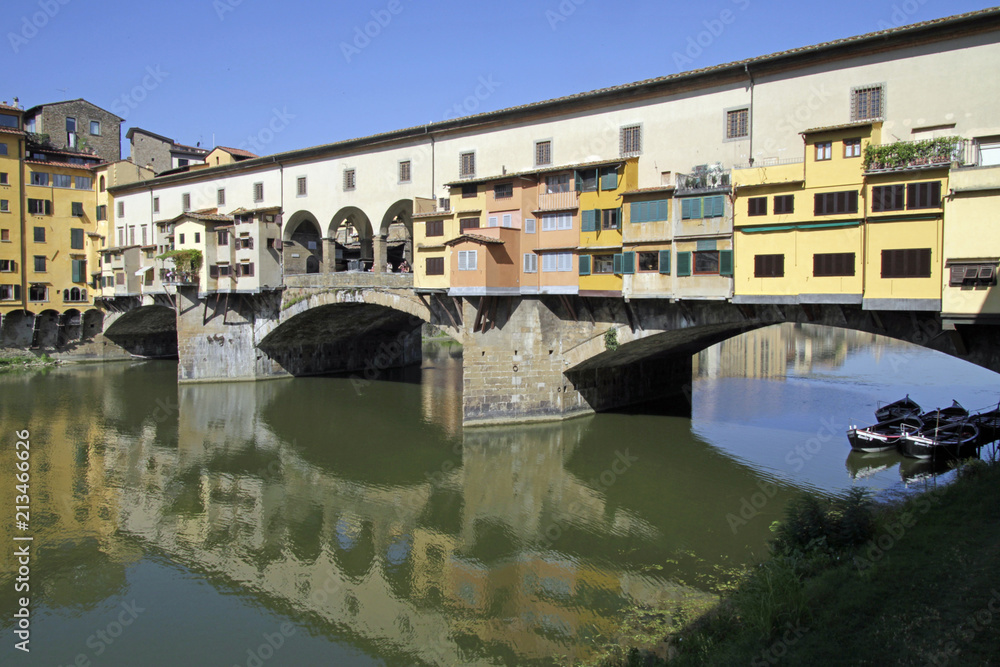 Ponte Vecchio in Florence, Italy, reflecting in the river Arno on a sunny day