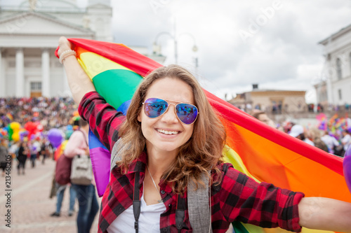 Smiling woman with rainbow flag in pride parade