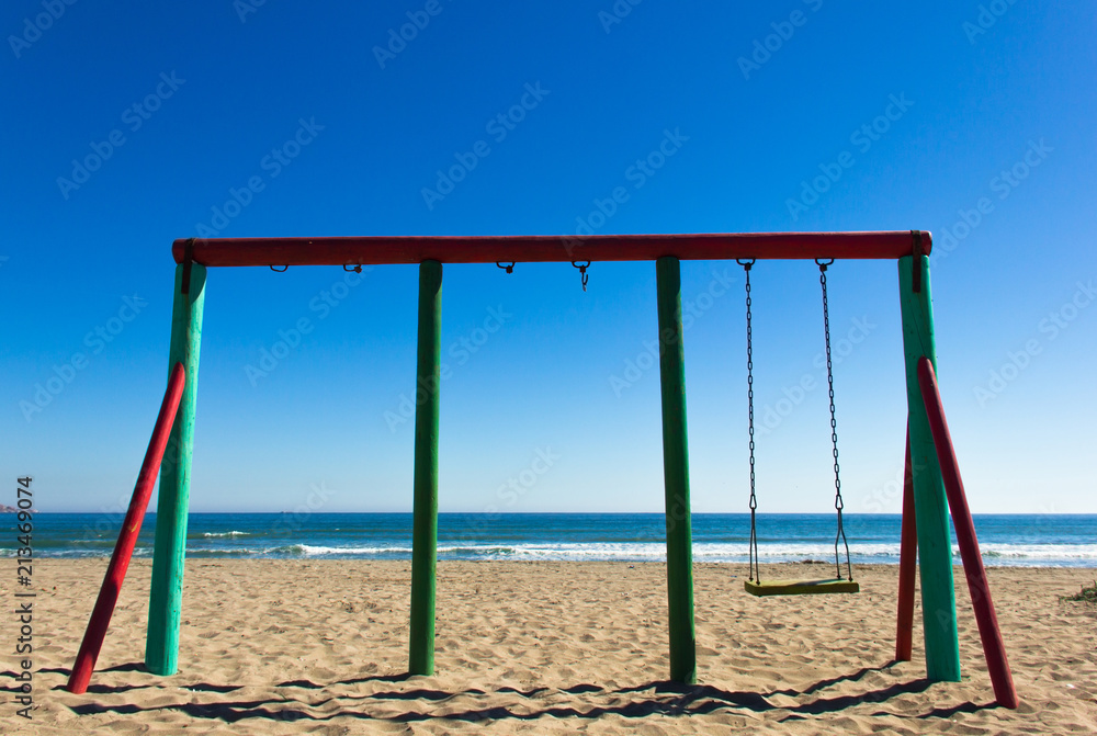 Single swing and two more missing on sunny winter day in La Serena beach, Chile. Kids playground by the sea