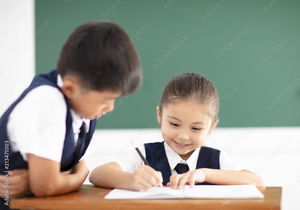 happy little girl writing homework in classroom happy little girl writing homework in classroom