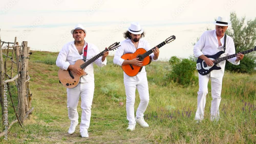Musicians in white clothes and white hats play the guitars. Cuban musicians on the coast. Musicians in white clothes and white hats play the guitars. Cuban musicians on the coast.
