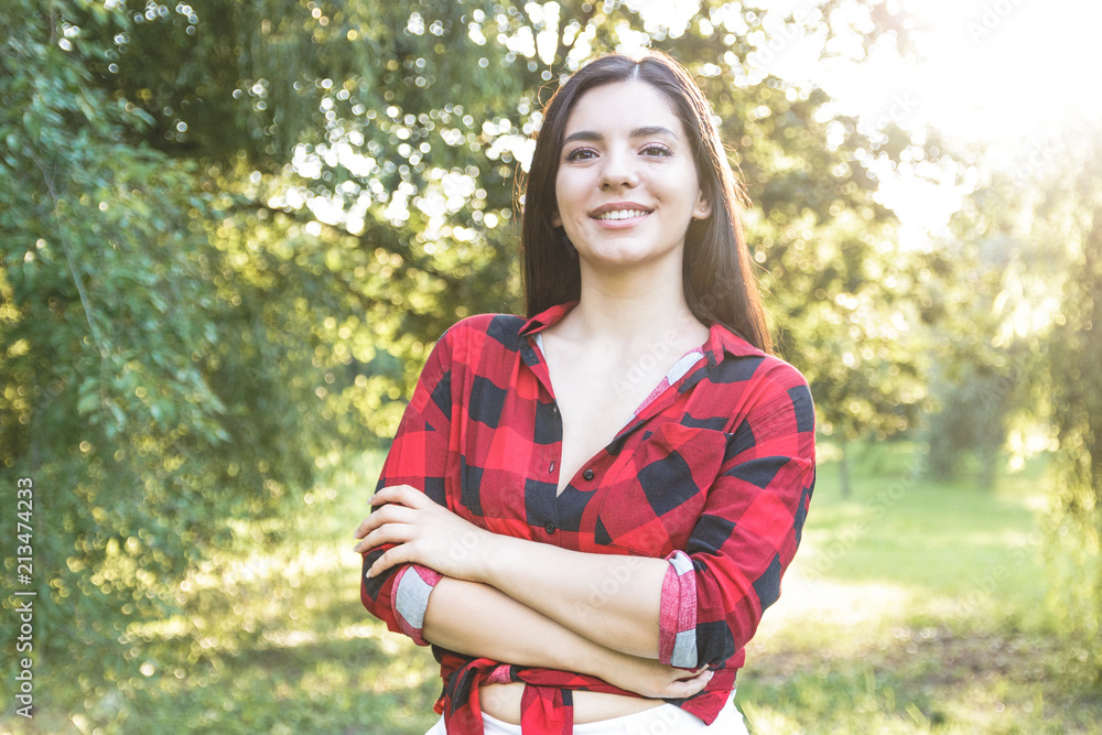 Smiling beautiful brunette girl in a red, plaid shirt, with arms crossed Smiling beautiful brunette girl in a red, plaid shirt, with arms crossed