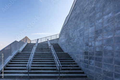 The modern urban stone stairway with the steel guardrails in the sunny day