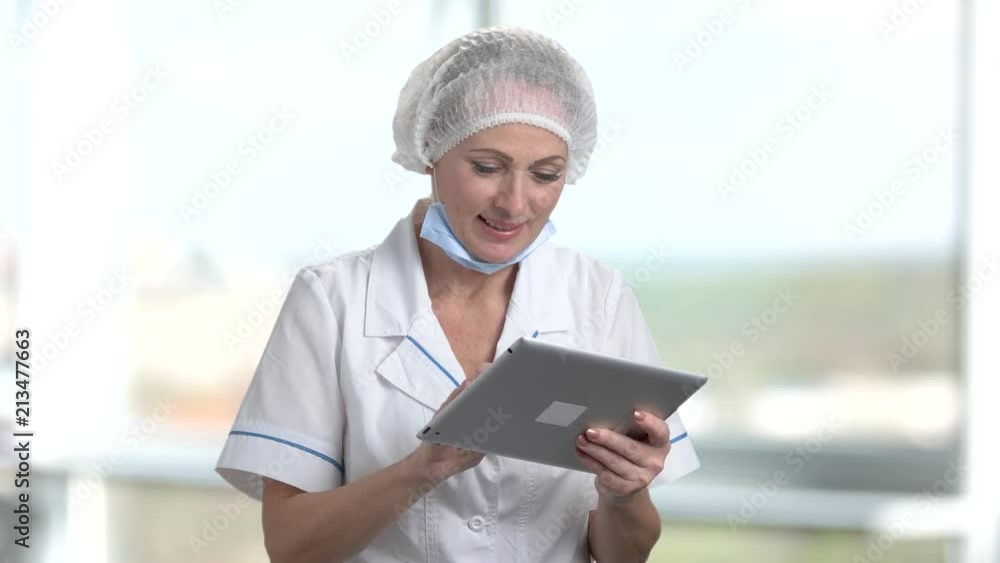 Happy female doctor with tablet. Smiling happy nurse using tablet indoor, bright windows background in hospital. Happy female doctor with tablet. Smiling happy nurse using tablet indoor, bright windows background in hospital.