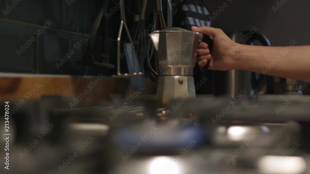 Slow motion shot of a woman moving moka pot Italian coffee maker towards the camera and placing it on the hob above the gas flame. Slow motion shot of a woman moving moka pot Italian coffee maker towards the camera and placing it on the hob above the gas flame.