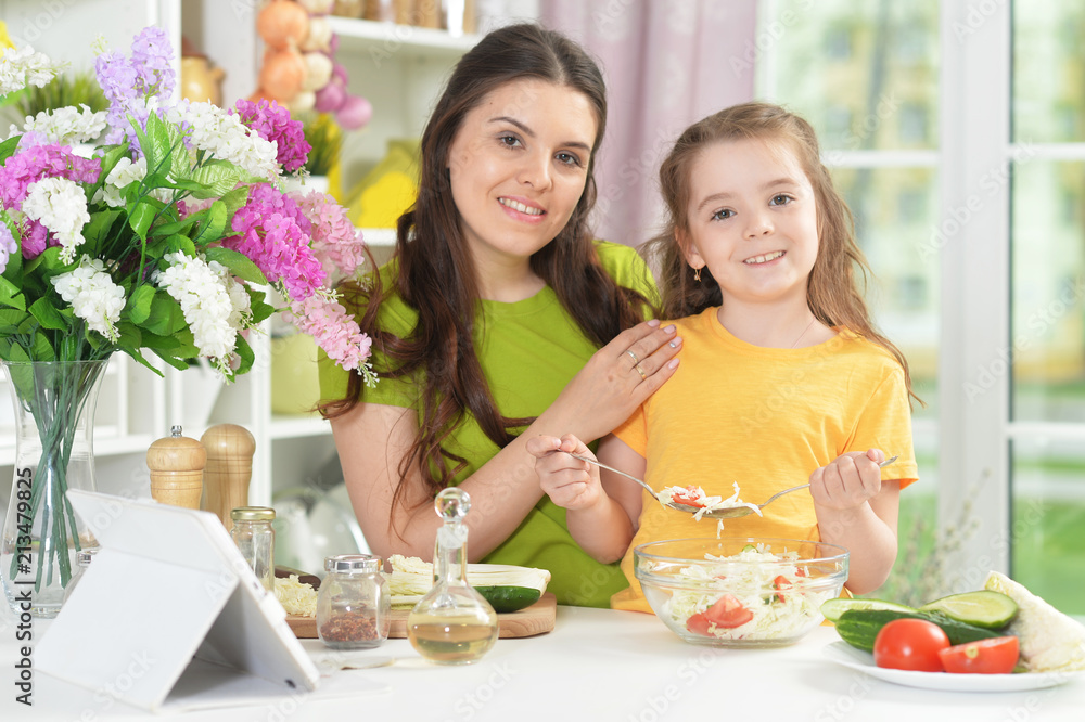 Cute little girl with her mother cooking together Cute little girl with her mother cooking together