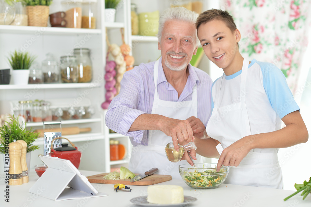 Senior man with grandson preparing dinner in kitchen