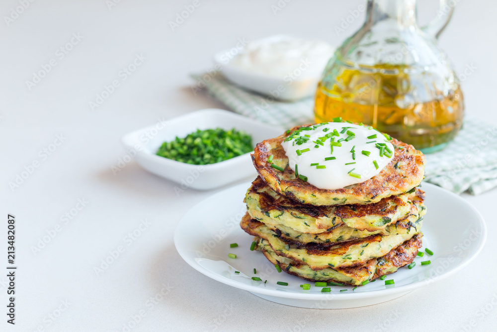 Vegetarian zucchini fritters or pancakes, served with greek yogurt and green onion on gray concrete background, horizontal, copy space Vegetarian zucchini fritters or pancakes, served with greek yogurt and green onion on gray concrete background, horizontal, copy space