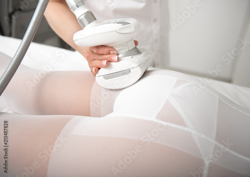 Close up assistant hand making treatment procedure for young female legs with special equipment