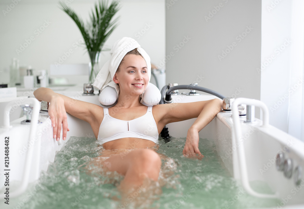 Naklejka premium Portret roześmiana młoda dama odpoczywa w zdroju salonie. Opiera się na kąpieli