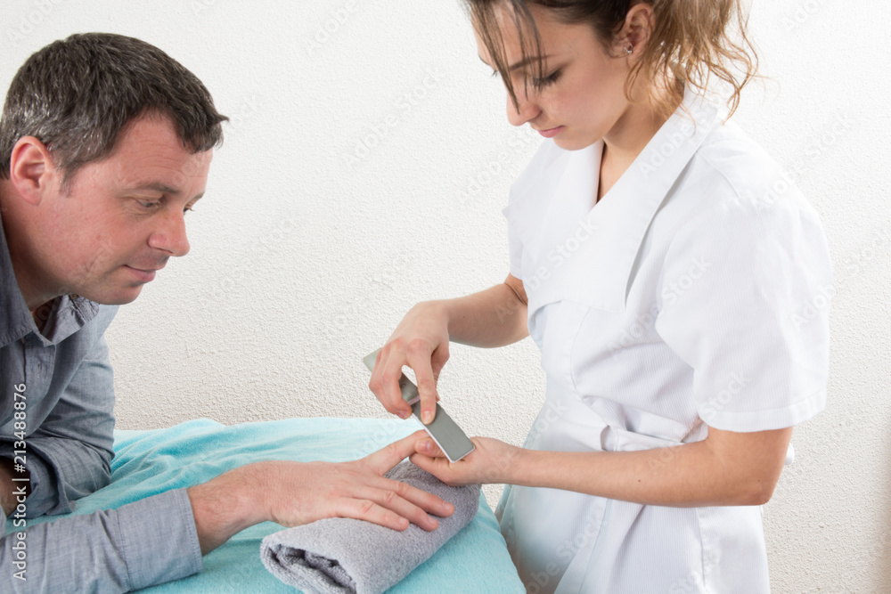 pretty beautician makes a manicure in the hands of handsome man pretty beautician makes a manicure in the hands of handsome man