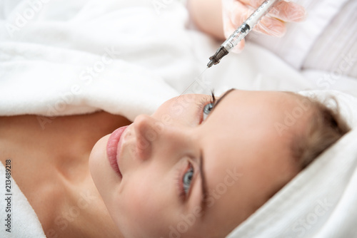 Outgoing woman getting facial beauty injection for rejuvenation. Cosmetology concept