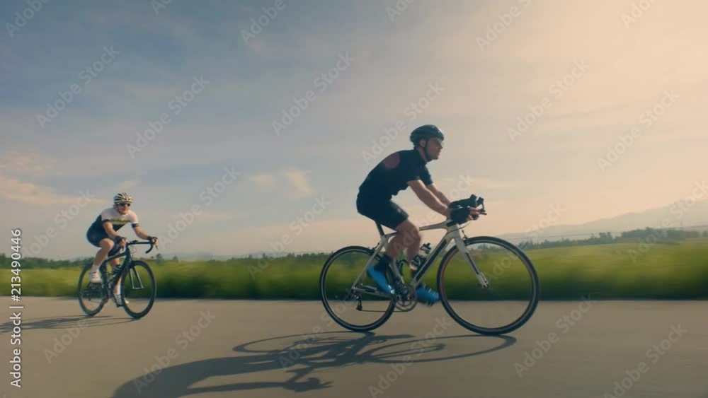 Close up, low angle, tracking shot of cyclists on countryside road Close up, low angle, tracking shot of cyclists on countryside road