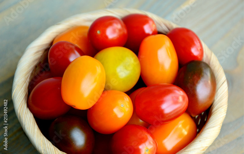 Tomato Varieties ,Type and color mixed together in basket on wooden floor.
A lot kind and different color of tomatoes.