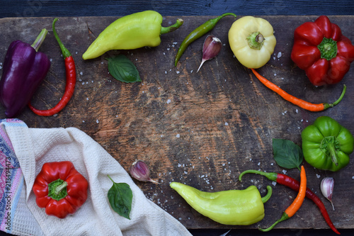 Bio organic fresh summer vegetables - different varieties of sweet and hot peppers on dark wooden background. Ingredients for cooking. Healthy food. Raw foodism. Copy space