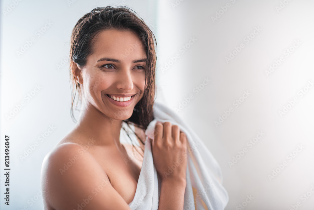 Portrait of optimistic lady touching head with arms while wrapping in fluffy towel Portrait of optimistic lady touching head with arms while wrapping in fluffy towel
