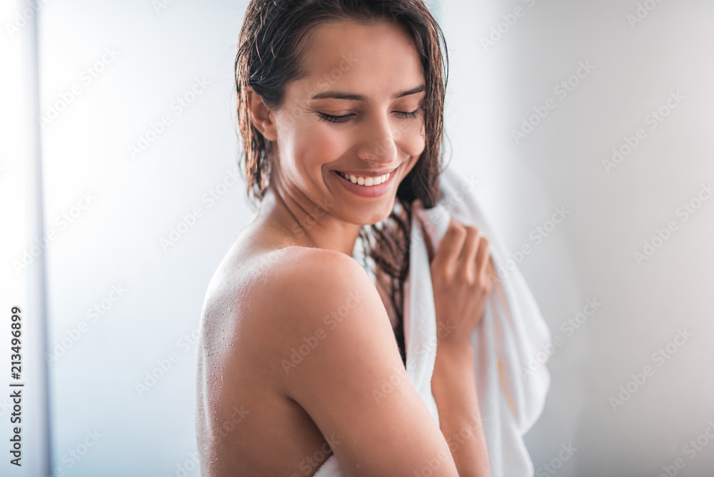 Portrait of cheerful woman standing after taking bath. She holding hair with hand Portrait of cheerful woman standing after taking bath. She holding hair with hand
