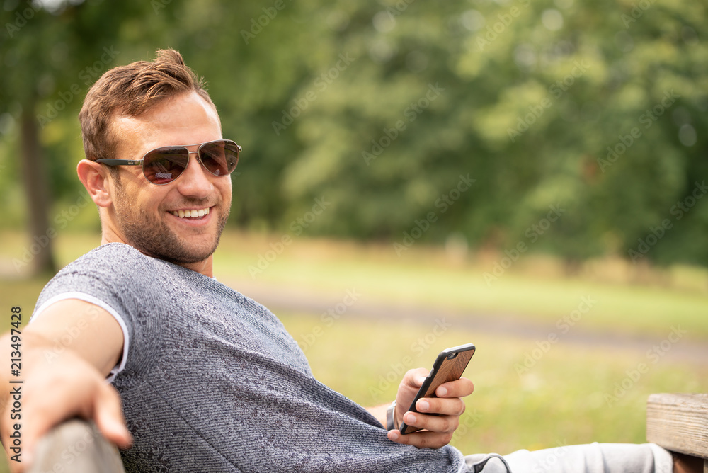 Fototapeta premium Mann draußen beim lachen und Smartphone in der Hand
