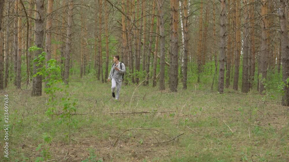young man with a backpack walks through the forest. Front view. young man with a backpack walks through the forest. Front view.
