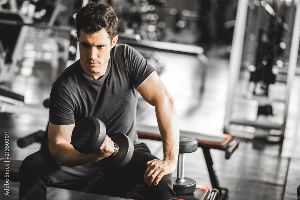 Fit caucasian handsome young man and big muscle in sportswear. Young man holding dumbbell during an exercise class in a gym. Healthy sports lifestyle, Fitness concept. Fit caucasian handsome young man and big muscle in sportswear. Young man holding dumbbell during an exercise class in a gym. Healthy sports lifestyle, Fitness concept.