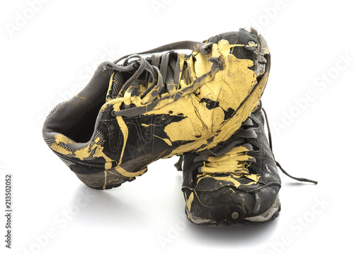 Pair of old paint covered training shoes on a white background