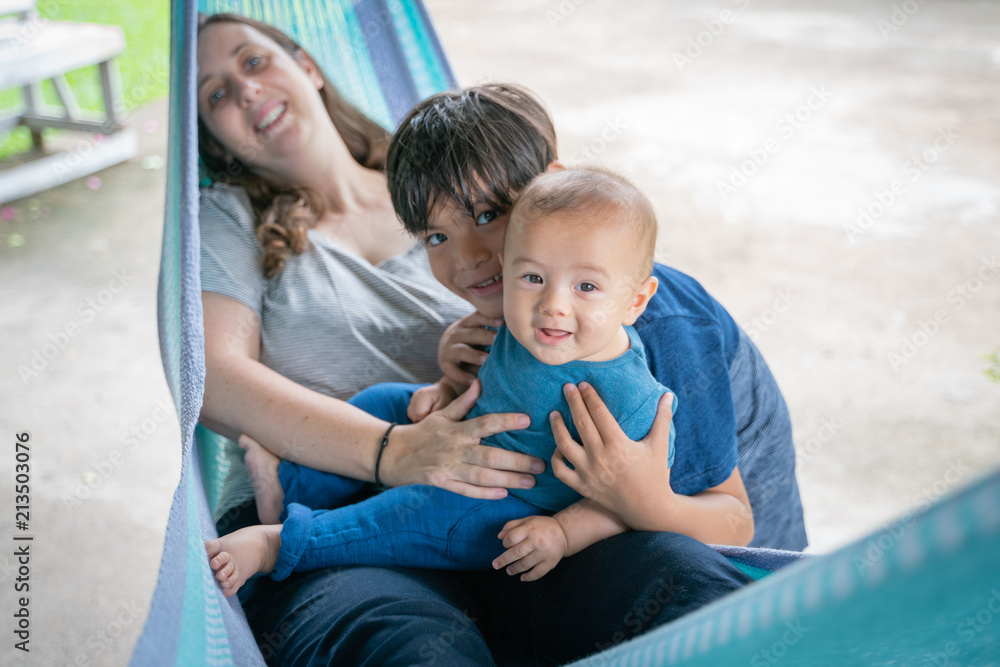 The little boy and mother are sitting at the hammock, both are happy The little boy and mother are sitting at the hammock, both are happy