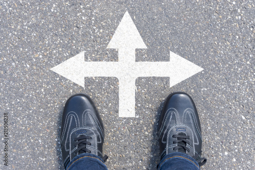 man standing on road with three direction arrow choices, left, right or move forward