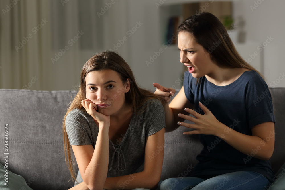 Woman scolding her friend who is looking at camera Woman scolding her friend who is looking at camera
