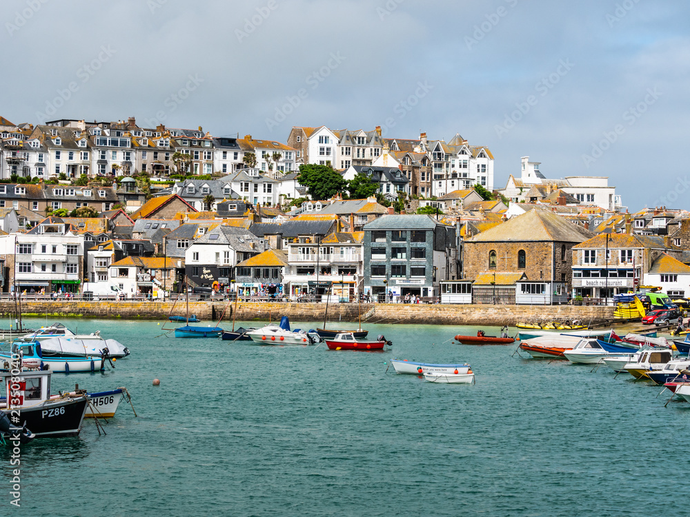 Lots of tourists visiting beautiful St Ives fishing harbour on a hot, sunny summer day in England.
