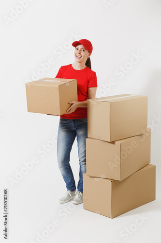 Full length portrait of delivery woman in red cap, t-shirt giving order boxes isolated on white background. Female courier near empty cardboard boxes. Receiving package. Copy space for advertisement.