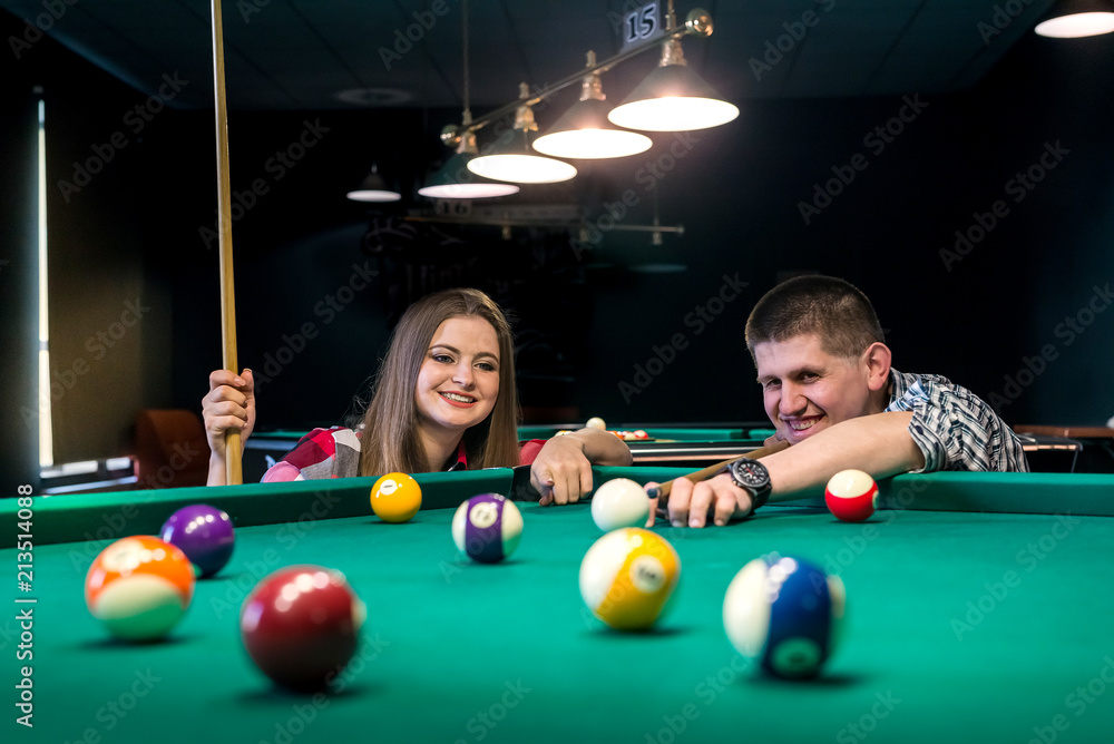 Fototapeta premium Friends playing billiard, man going hit a ball