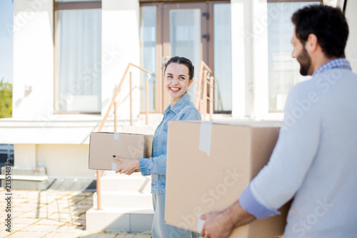 Happy young woman with box talking to her husband while helping to relocate © pressmaster